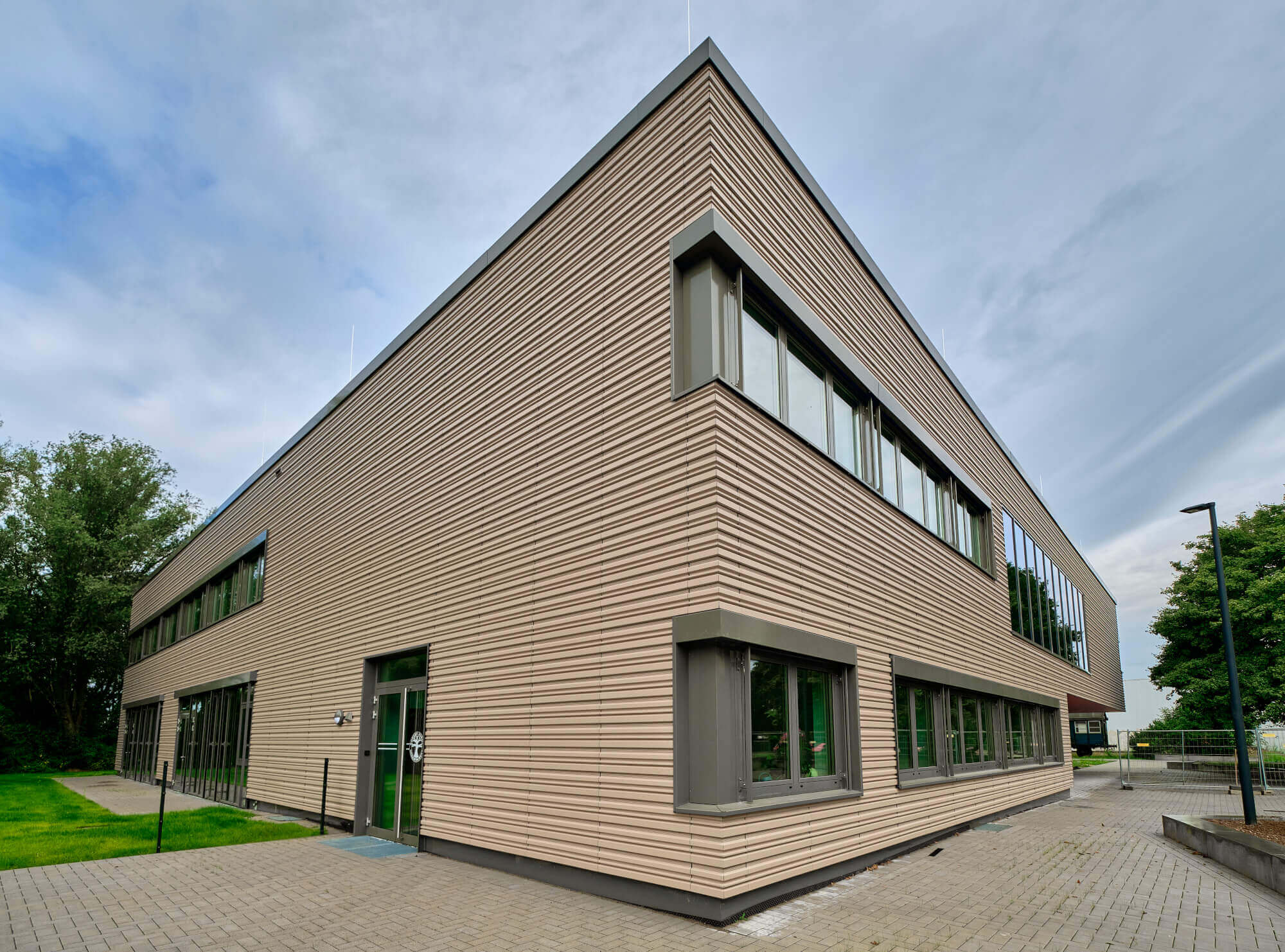 Tonality Referenz Gesamtschule Krefeld - Keramikfassade Eckenansicht mit Blick auf das moderne, architektonisch ansprechende Gebäude mit Terrakotta-Verkleidung