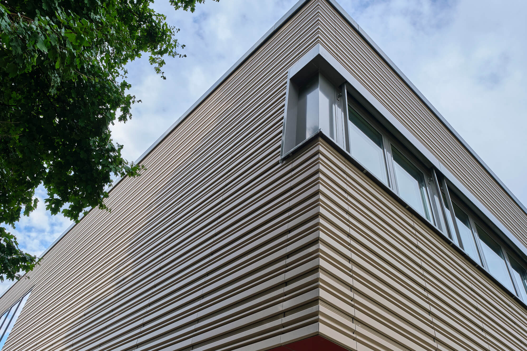 Tonality Referenz Gesamtschule Krefeld: Keramikfassade an Gebäudeecke mit abwechselnden Terrakotta-Tönen und lebendiger Strukturierung