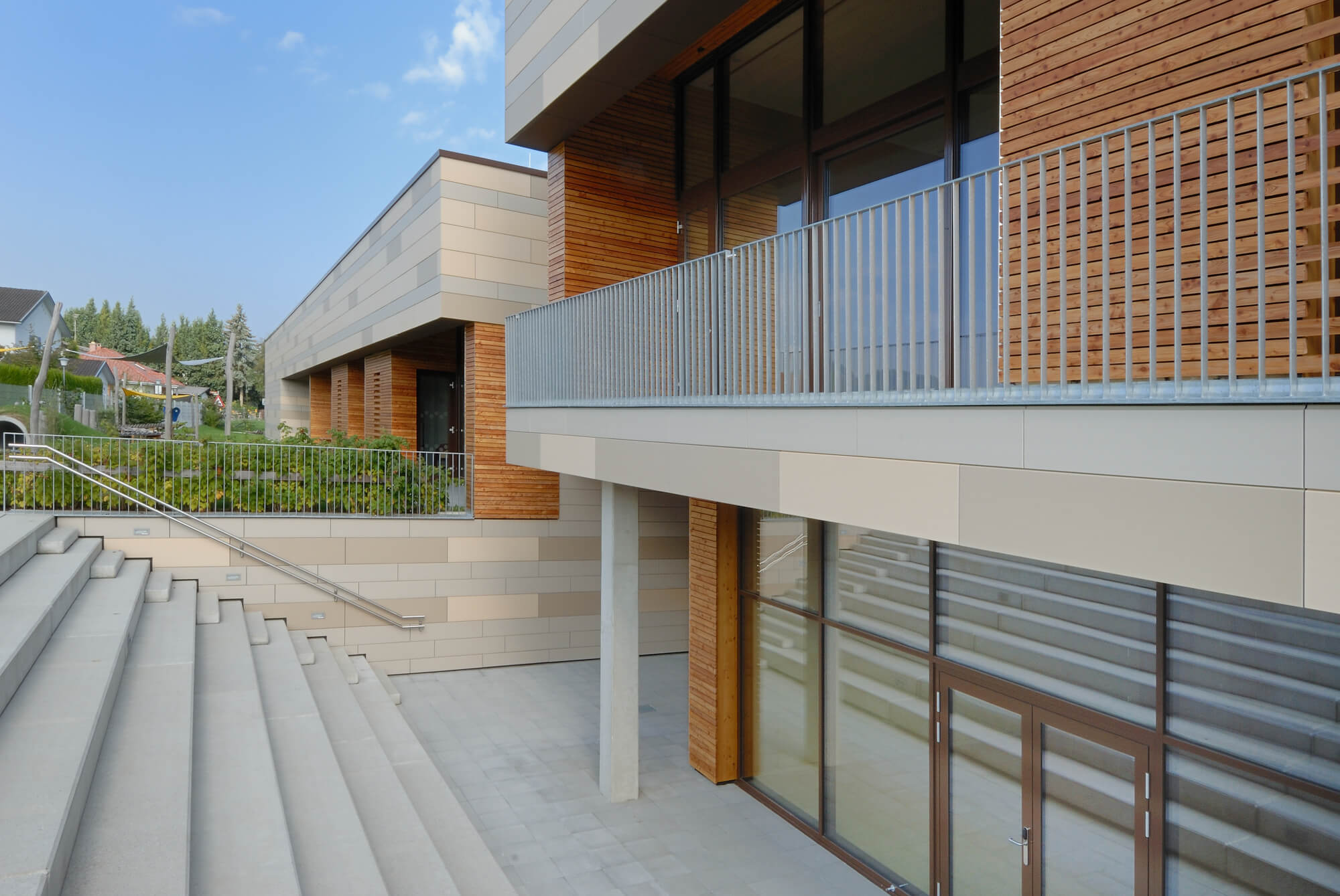 Tonality Referenz: Keramik Fassade Kinderhaus Pertinsel Treppe - moderne und nachhaltige Architektur mit roter Tonality Fassade und eleganten Stufen