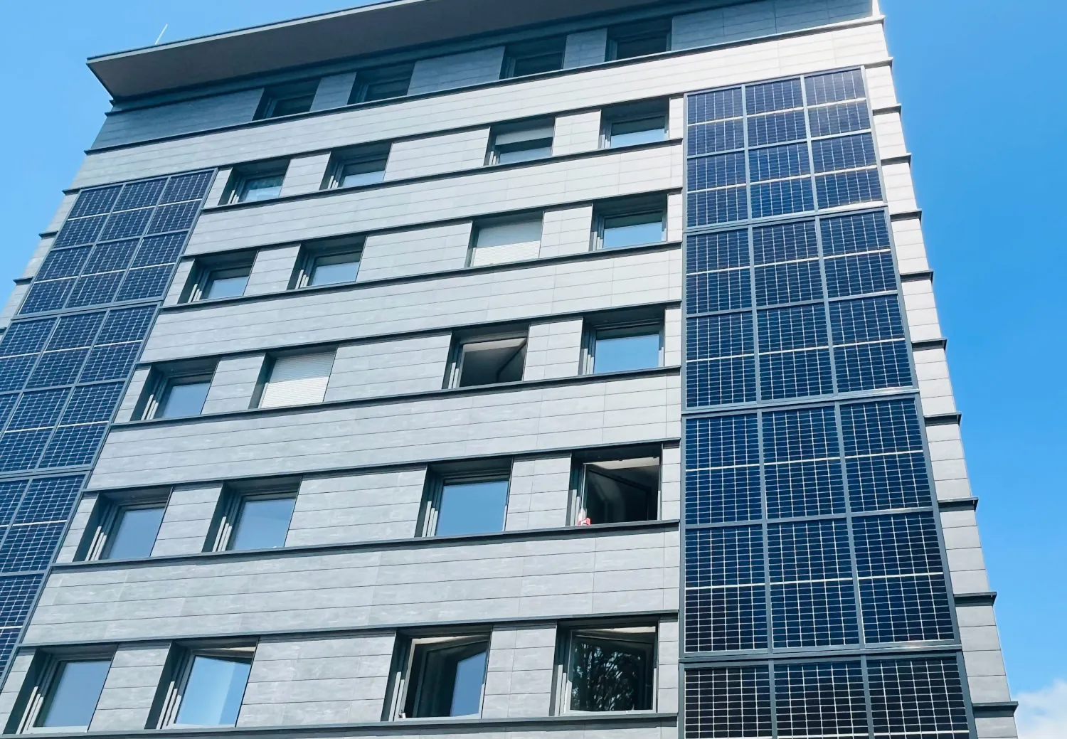 Nahaufnahme der sanierten Keramikfassade eines Gebäudes in Lindau mit grauen Platten und Solarpaneelen