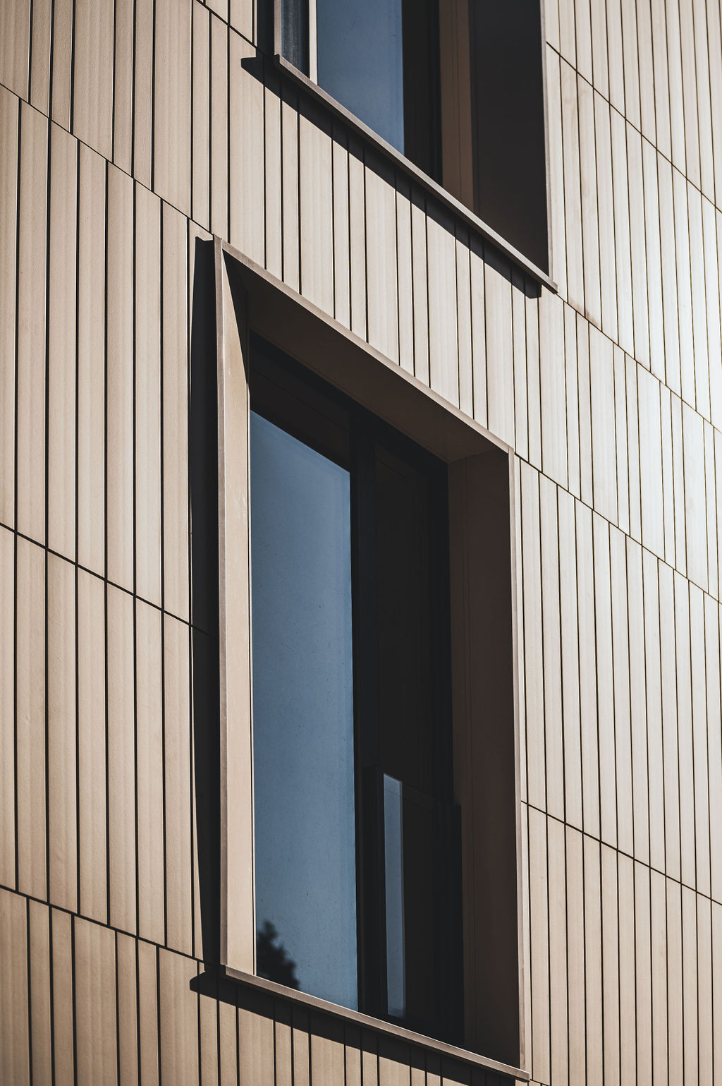 Detailaufnahme der Keramikfassade des Baerahus in Feldkirch mit vertikalen Linien und großen Fenstern