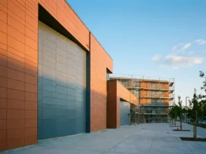 Neues Schulgebäude mit geometrischer Keramikfassade in Terrakotta und Schiefergrau im goldenen Nachmittagslicht.