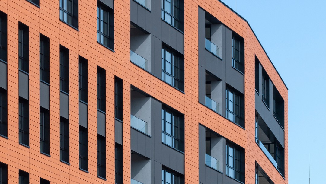 DOKI Living mit glatter Tonality Keramikfassade in Ziegelrot und Hellrot.