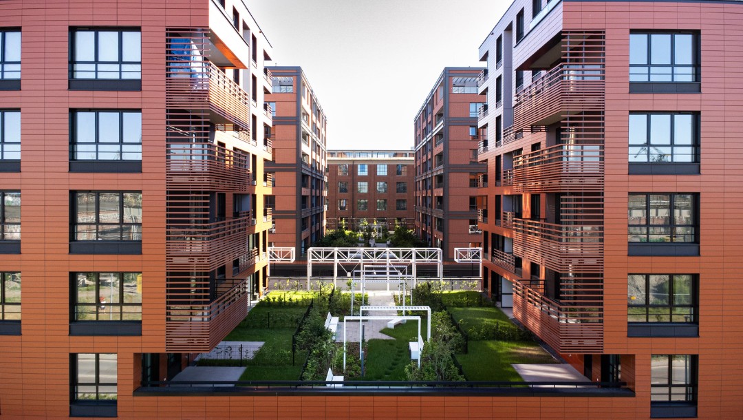 DOKI Living mit glatter Tonality Keramikfassade in Ziegelrot und Hellrot.