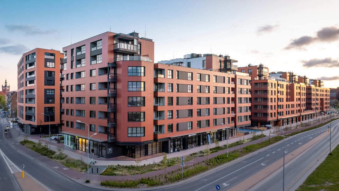 DOKI Living mit glatter Tonality Keramikfassade in Ziegelrot und Hellrot.